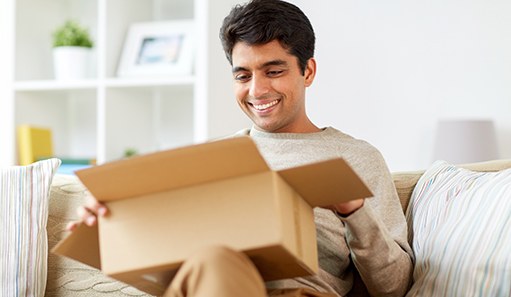 Man sitting on couch looking at an open package