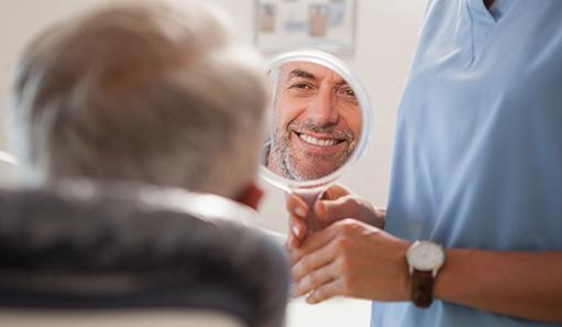 Man smiling at reflection in handheld mirror