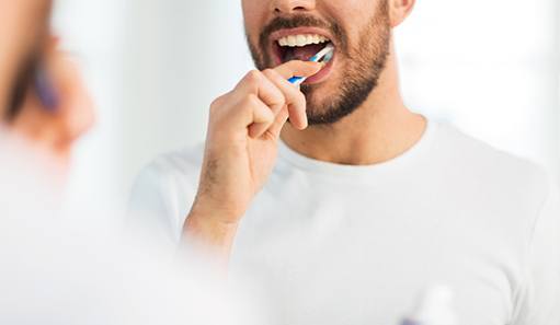 Man smiling while brushing his teeth