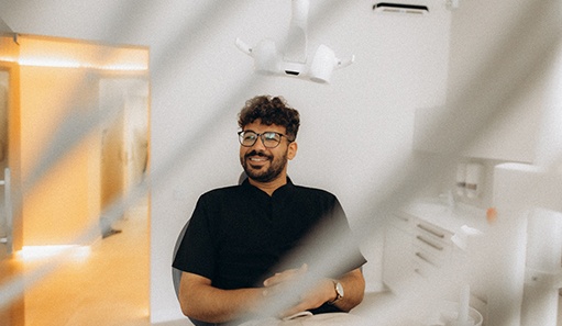 Patient with black glasses smiling in treatment chair