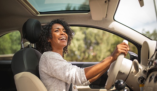 Woman smiling while driving on sunny day