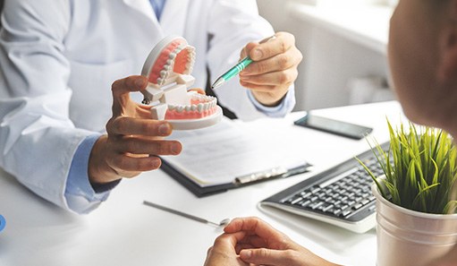 Dentist showing patient model of teeth