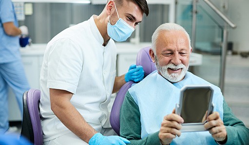 Man smiling at reflection next to dental assistant