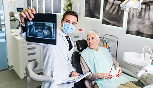 Dentist reviewing X-ray with smiling patient