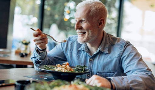 Man smiling while eating lunch at restaurant