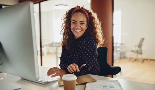 Woman smiling while working on computer in office