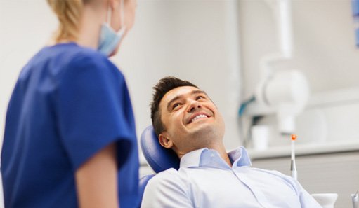 Man smiling at dental assistant while sitting in treatment chair