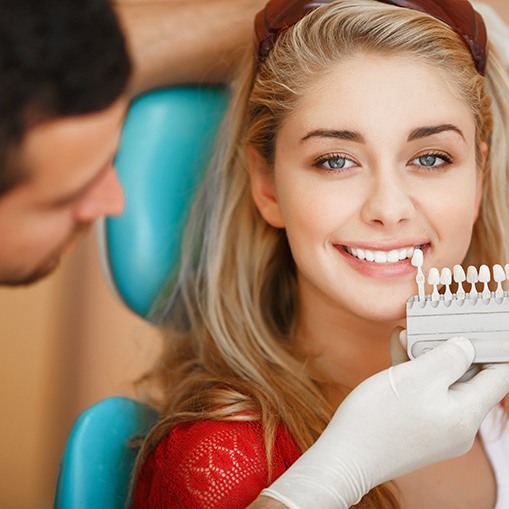 A dentist assessing the shade of a woman’s smile