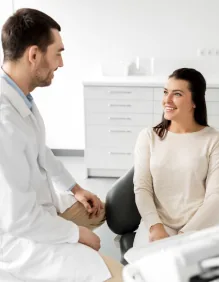 Woman in a white sweater sitting in dental chair and talking with her dentist