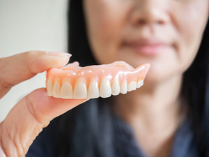 Close-up of woman holding a full denture